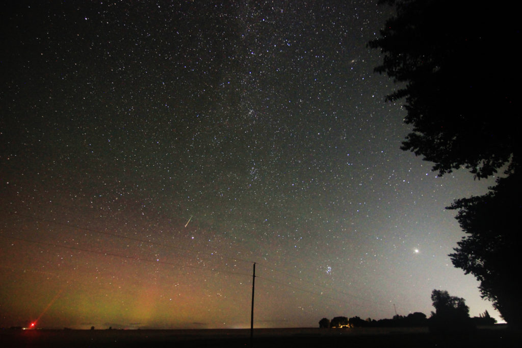 A meteor streaks above the aurora