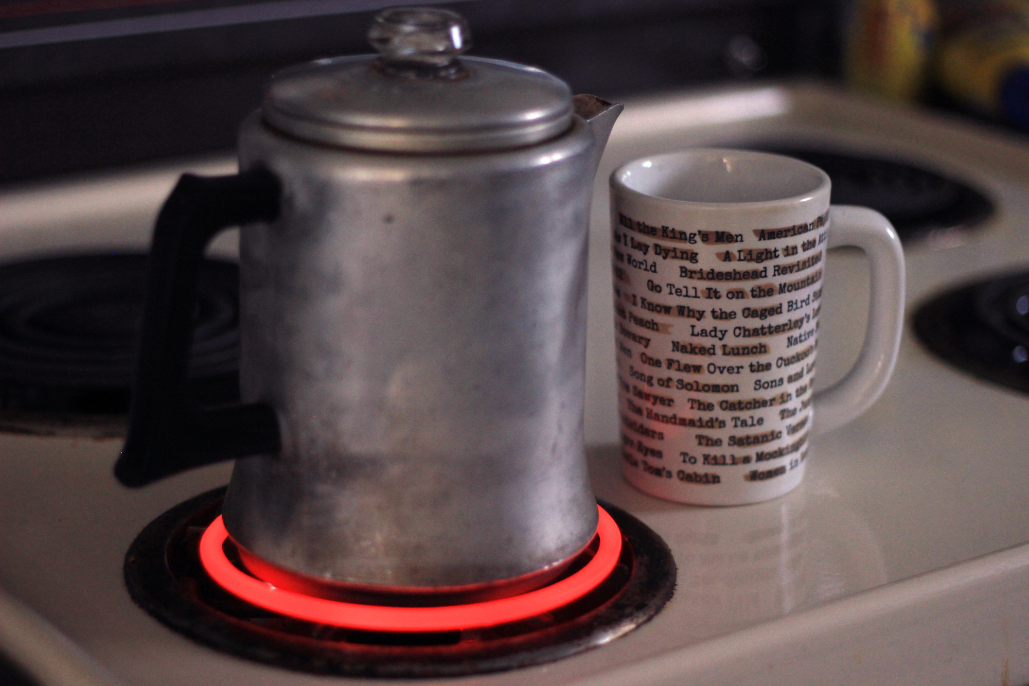 My older-than-I-am coffee percolator on a red-hot burner on my stove, next to my Banned Books mug