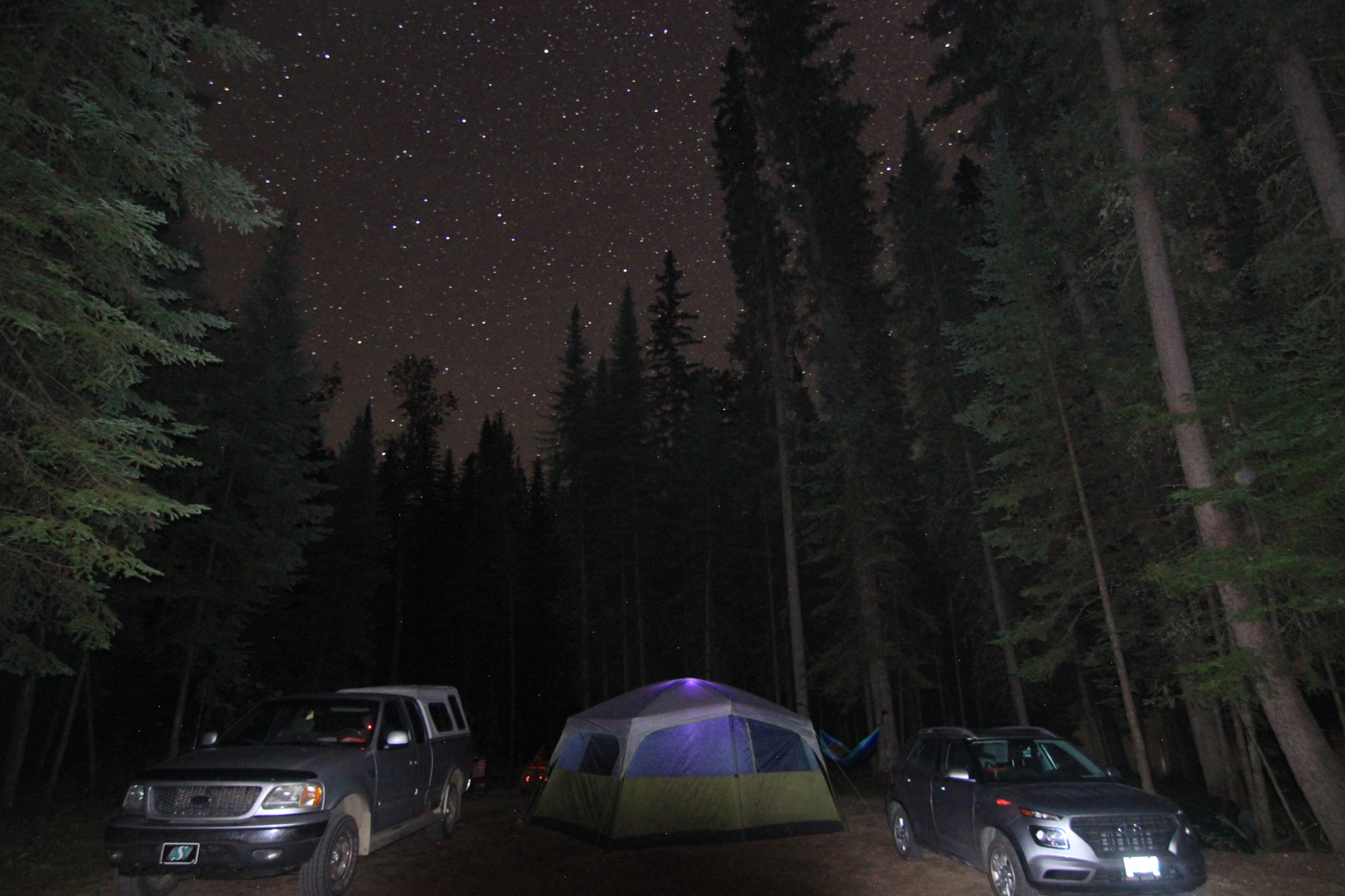 The tent and two vehicles, with the stars above them
