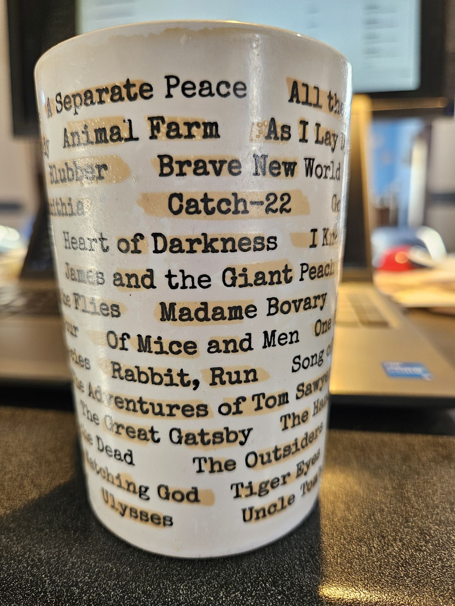 A mug with the titles of banned books on it, including Animal Farm, Catch-22, Heart of Darkness, and James and the Giant Peach